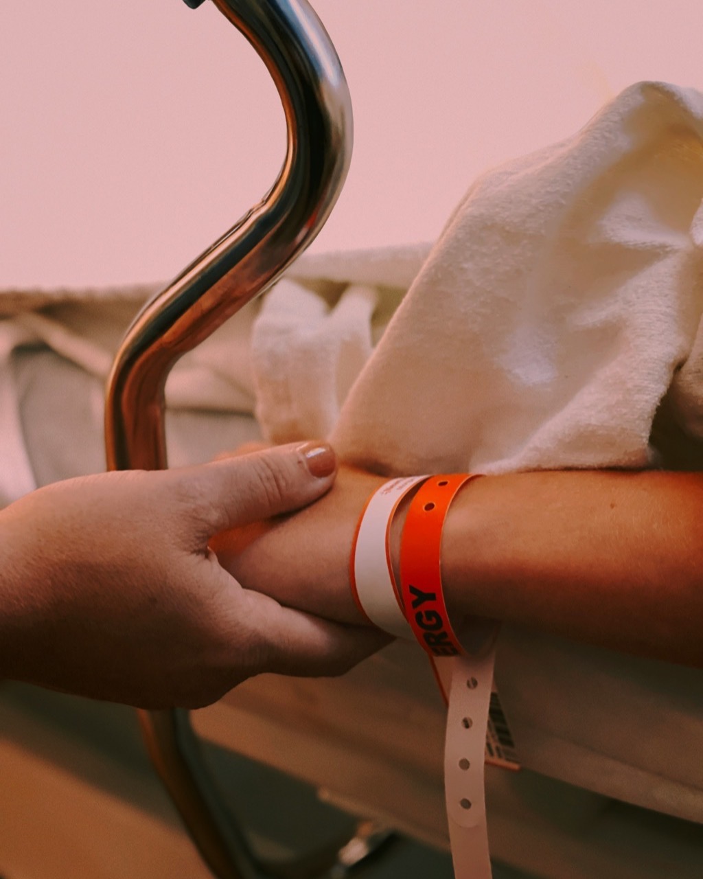 An advocate holds the hand of a patient resting in a hospital bed